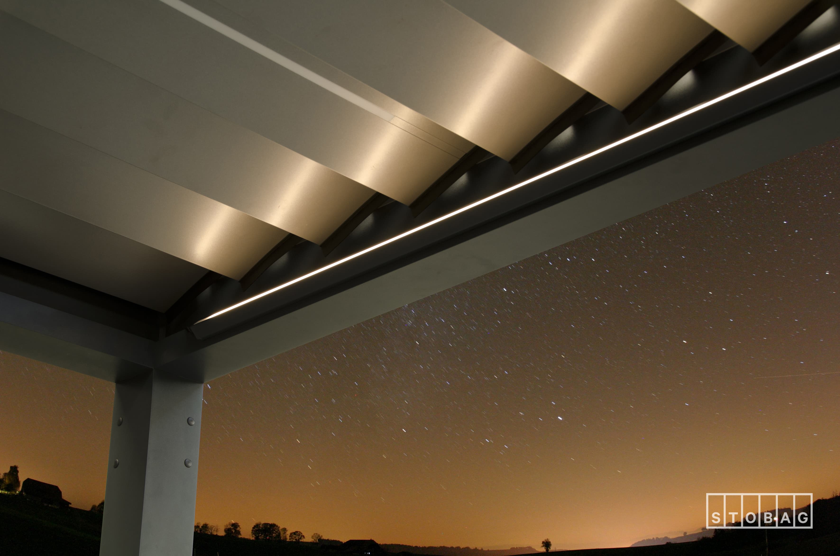 Louvered roof structure with integrated LED lighting at dusk