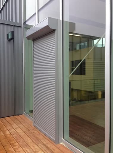 Clear anodized rolling shutter integrated into a building elevation
