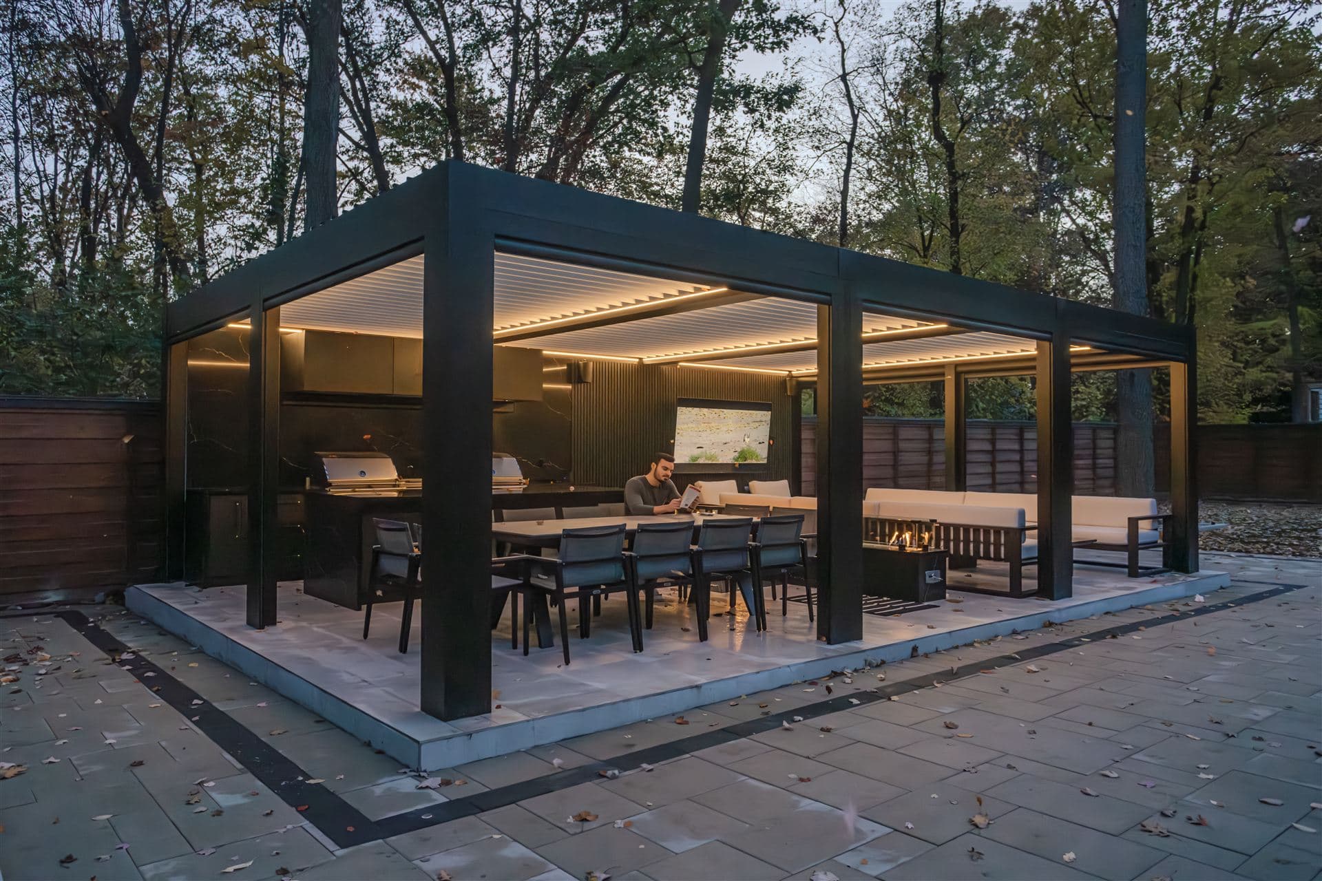 LOUSOL multi-module pergola over a complete outdoor living room with kitchen and TV