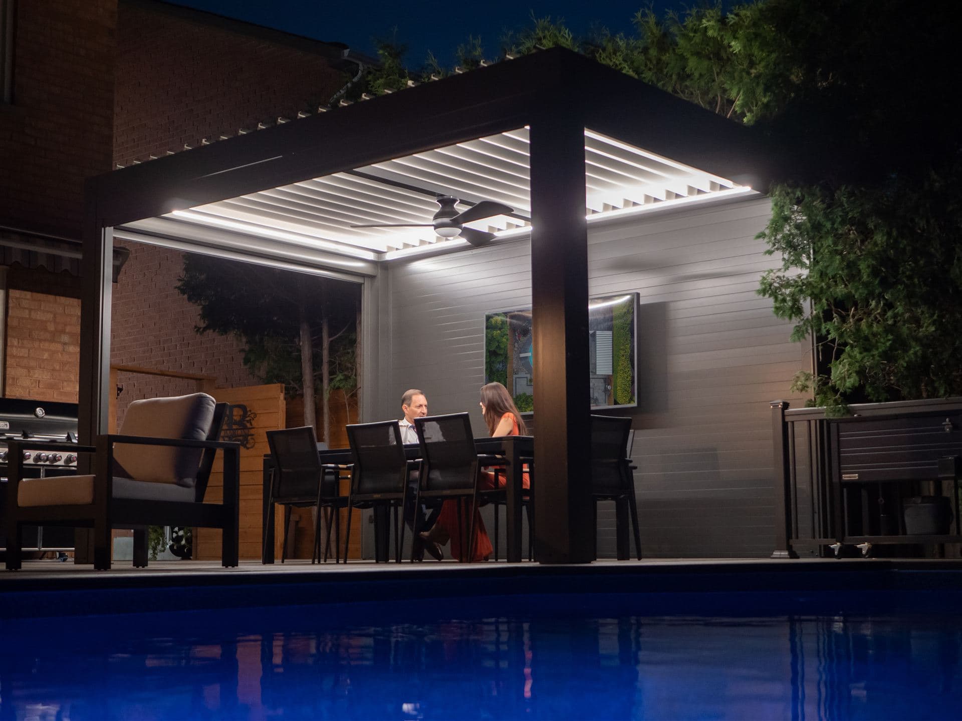 LOUSOL pergola at night with LED lighting and outdoor TV