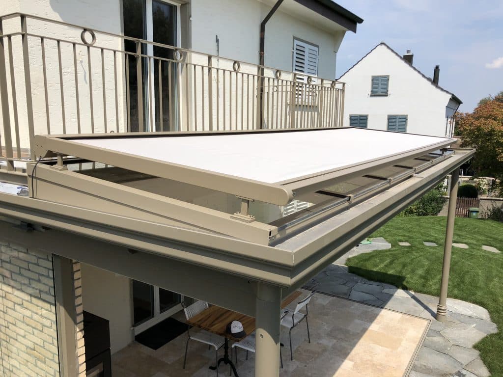 Motorized conservatory awning mounted on glass sunroom roof