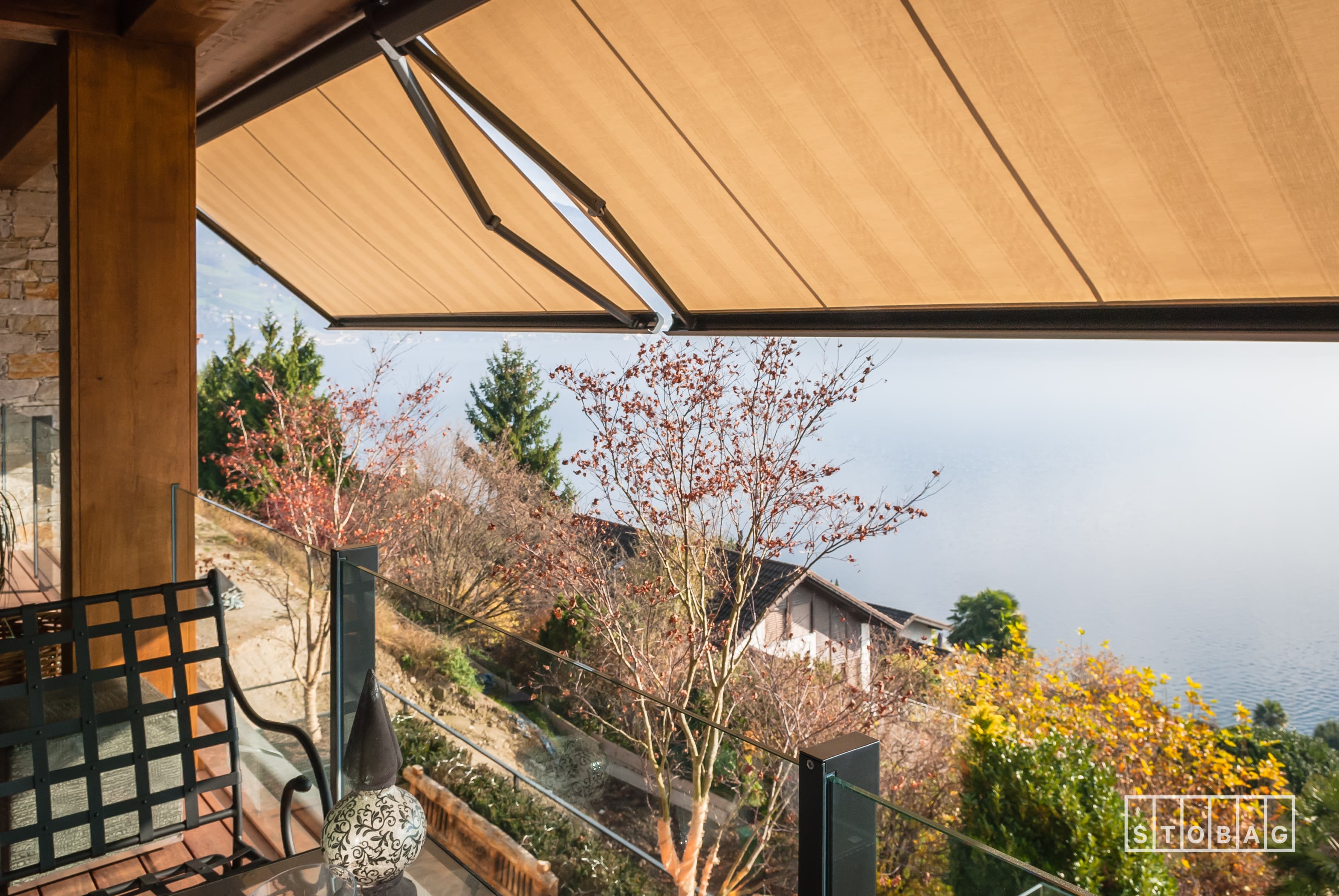 Retractable cassette awning extended over a terrace with a lake view