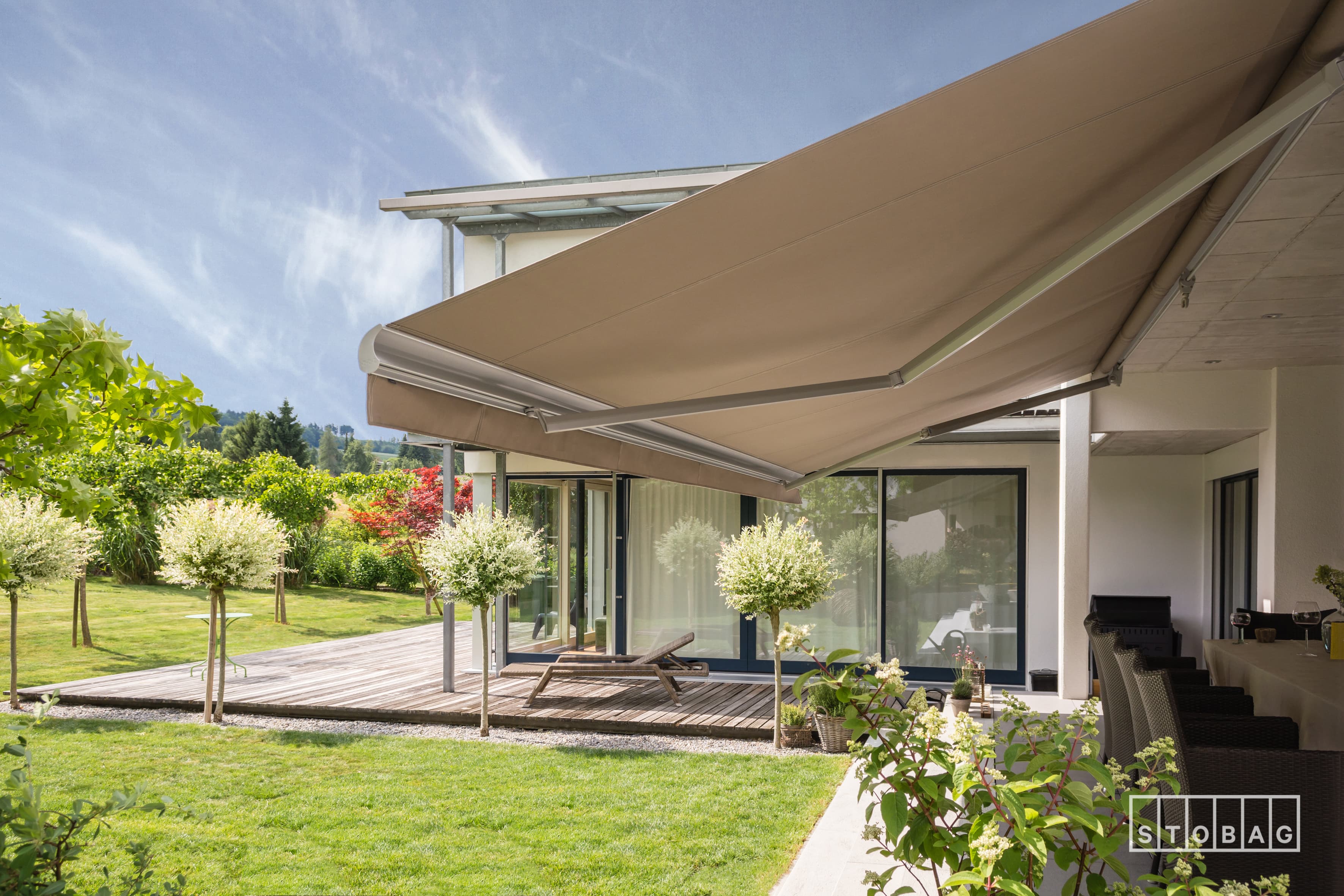 Open retractable awning with lateral arms on residential deck